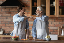 Millennial man and older father laugh in the kitchen