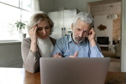 Man and woman looking stressed while staring at laptop
