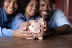 Man, woman, and child holding a piggy bank