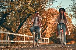 A young couple cycle through a park