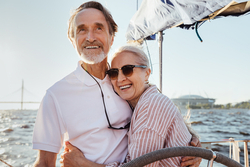 An older couple hugging on a boat. 