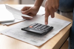 A person going through paperwork with a calculator. 