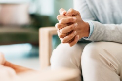 A woman sitting with her hands clasped.