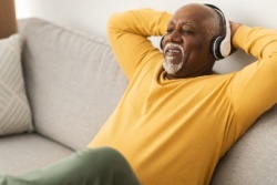 A man relaxing on a sofa with his hands behind his head.