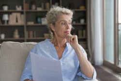 A woman looking pensive over paperwork.