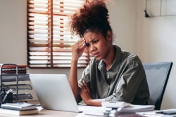 A woman on her computer looking stressed.