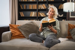 Smiling lady sitting on a sofa reading a book