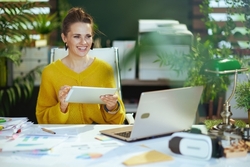 A woman on her computer surrounded by plants.